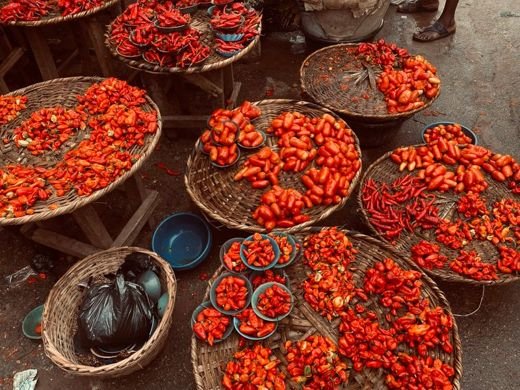 Array of vibrant red peppers in baskets at an outdoor market. Perfect for food and spice themes.