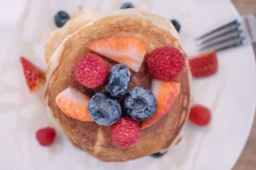 Close-up of fluffy pancakes topped with fresh berries. Healthy and tasty breakfast option.